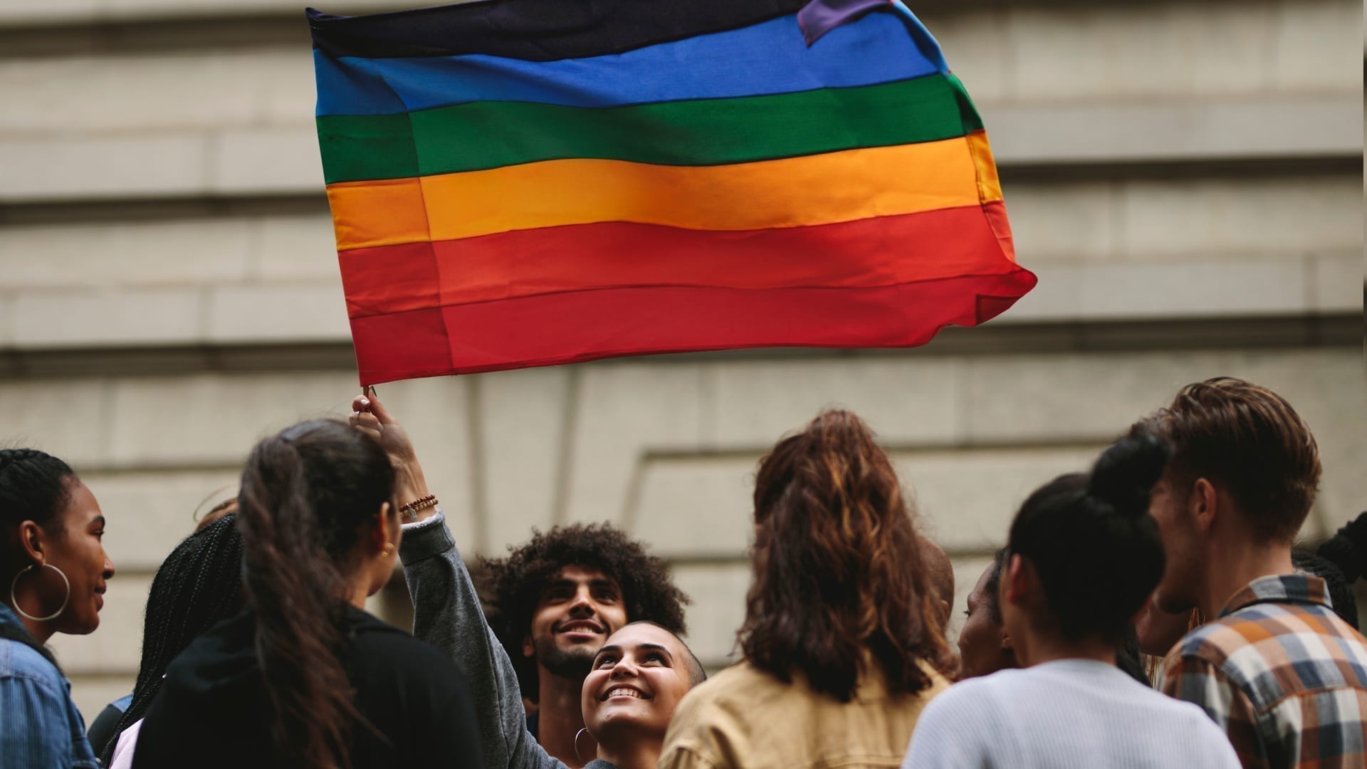 What's Your Story - group of young people holding up Pride flag