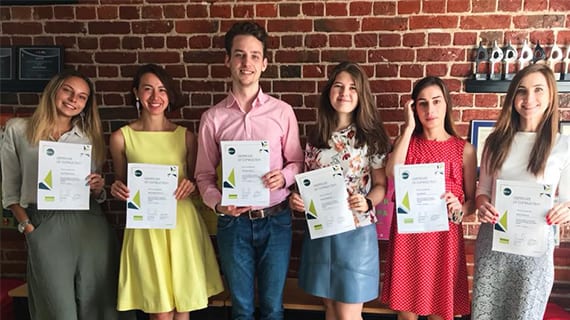 A group of female and male Ketchum Moscow colleagues holding sheets of paper that say Ketchum