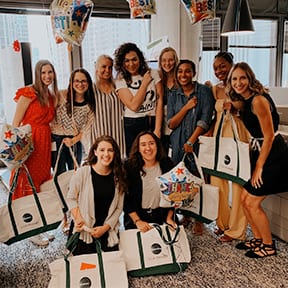 A group of females holding tote bags with the Ketchum logo on it