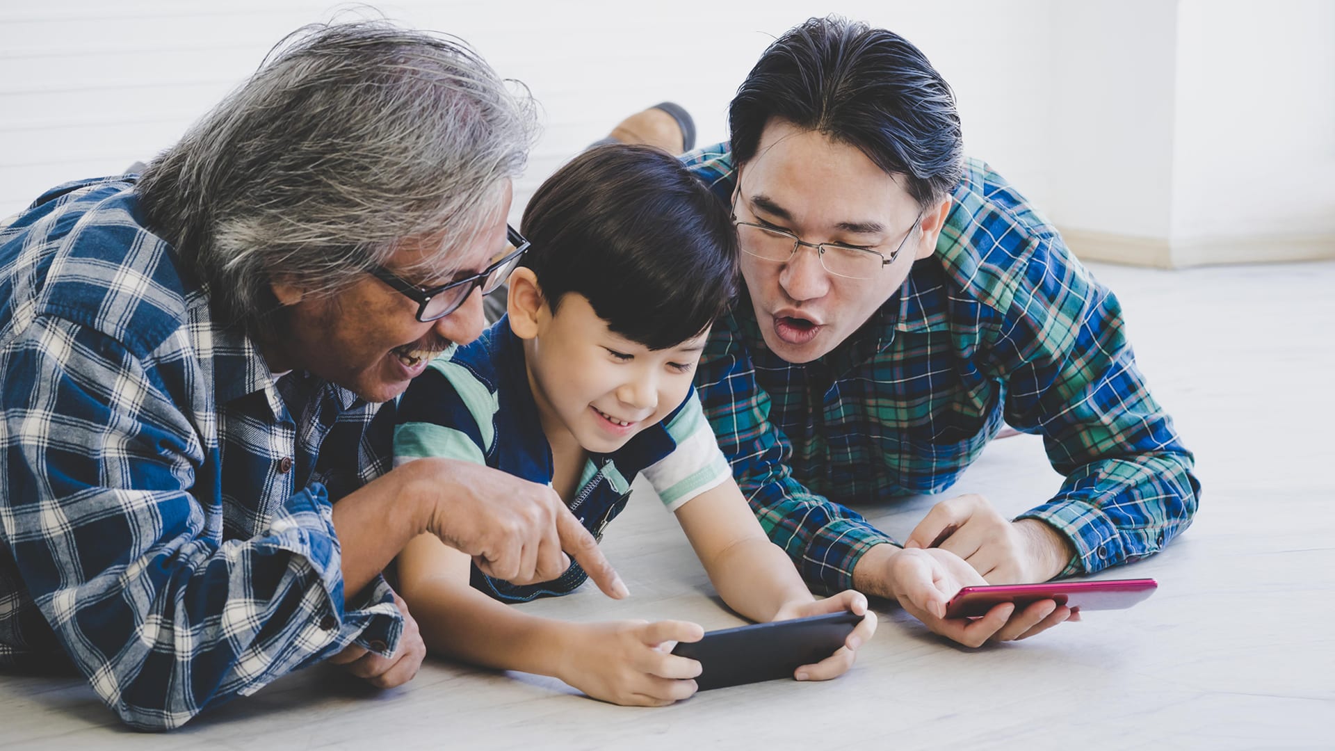 Grandfather, grandson and father looking at smartphones