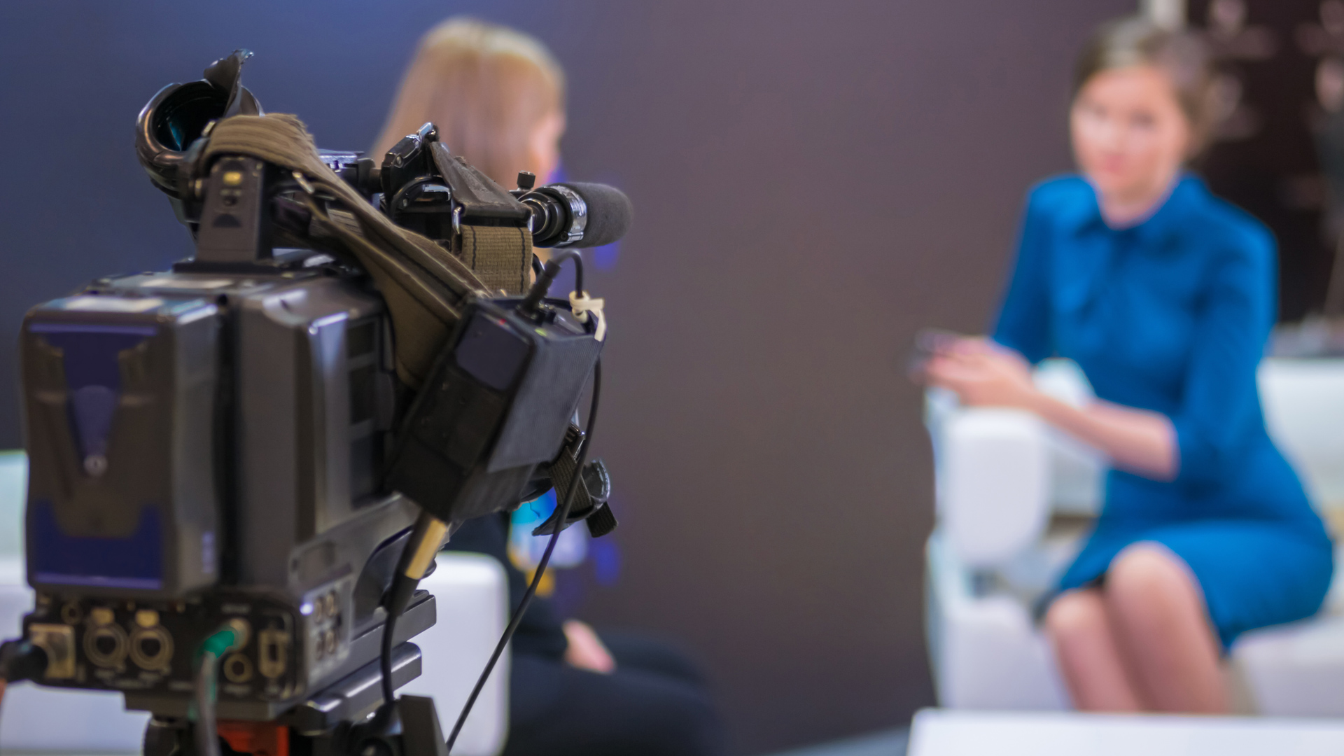In-person Media Interviews Are Back (If You’re Prepared) - photo of a video camera filming a TV interview between two female participants