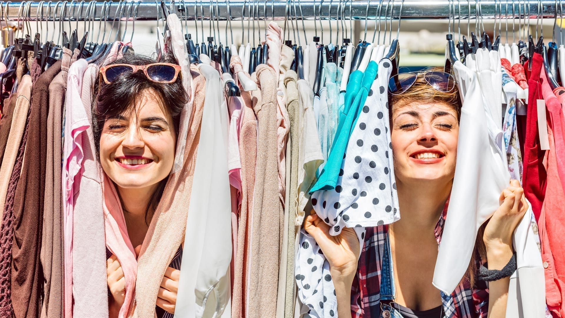 Retail Influencers and the Power of Personalization - two young women playfully posing with a clothes rack