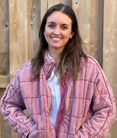 Woman standing outside smiling with pink jacket