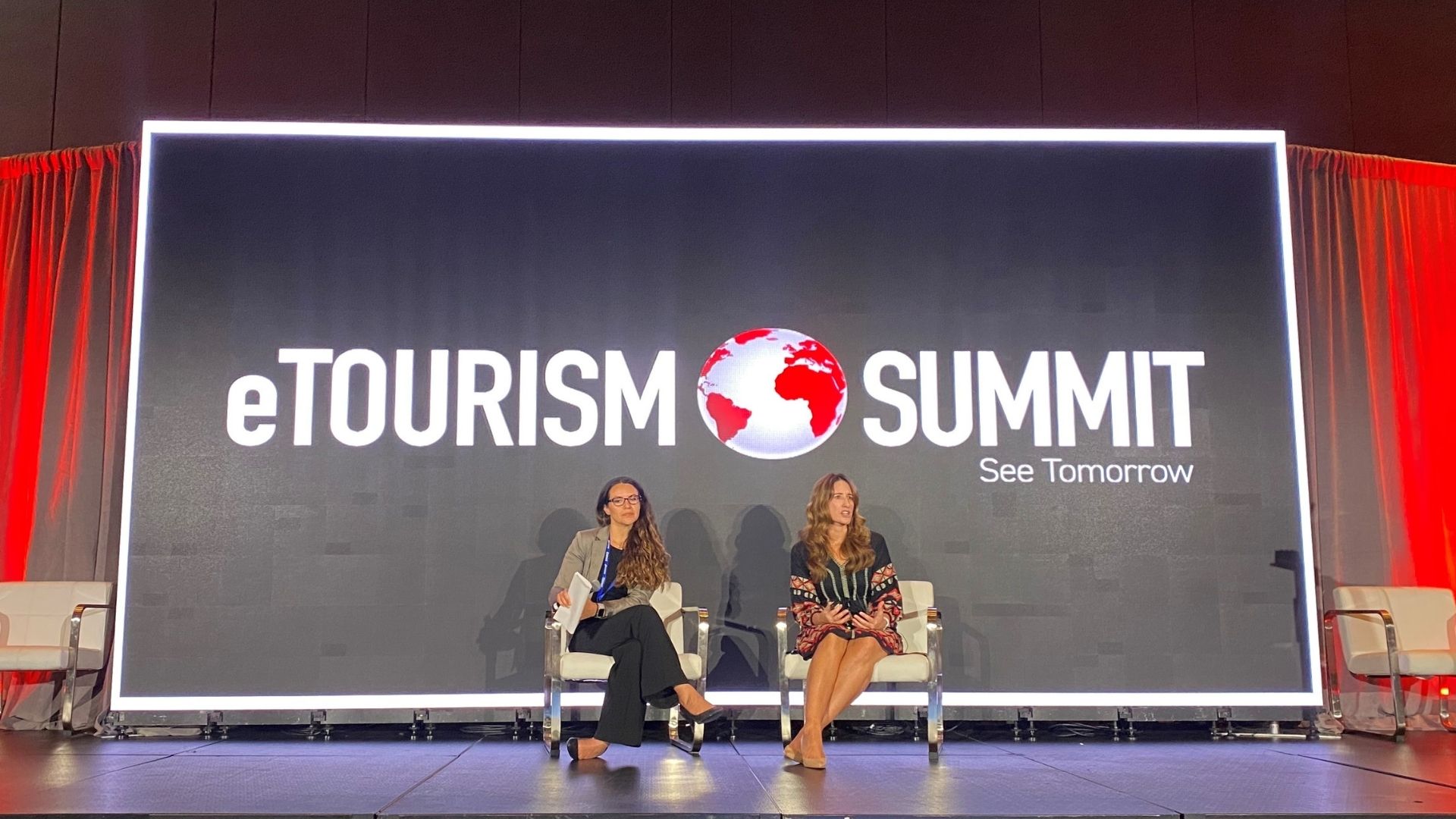 A photo of Bettina Garibaldi, SVP, managing director, Ketchum Travel, Hospitality & Leisure, and Leah Chandler, chief marketing officer of Discover Puerto Rico, sitting on stage at the e-Tourism Summit, discussing using the power of third parties to lift your brand